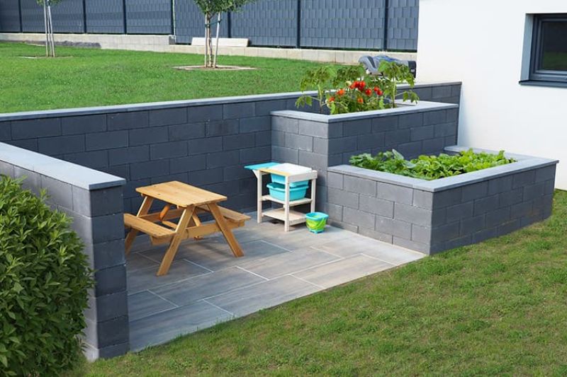 Stackton Stützmauer mit zwei unterschiedlich hohen Hochbeeten und einem Sitzbereich in Anthrazit steinglatt