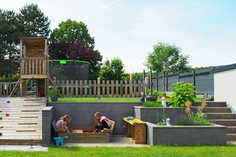 Stackton Stützmauer kombiniert mit einem Hochbeet in Anthrazit steinglatt und einem Spielplatz